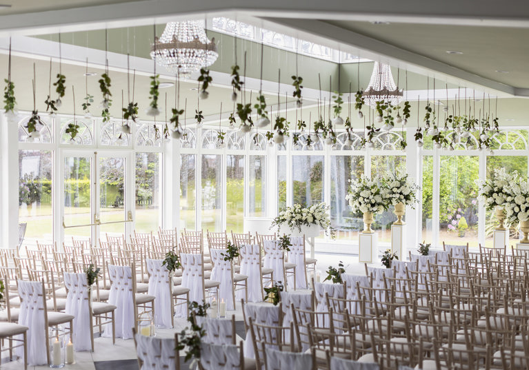 Wedding ceremony room with many windows, natural light and floral decor